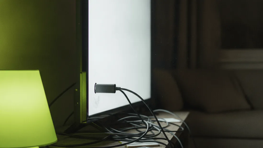 A television stand with a streaming stick, tangled cables, a remote, and a lime green lamp at night.